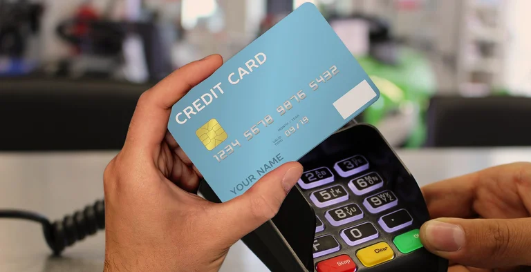 A hand tapping a contactless bank card on a payment terminal