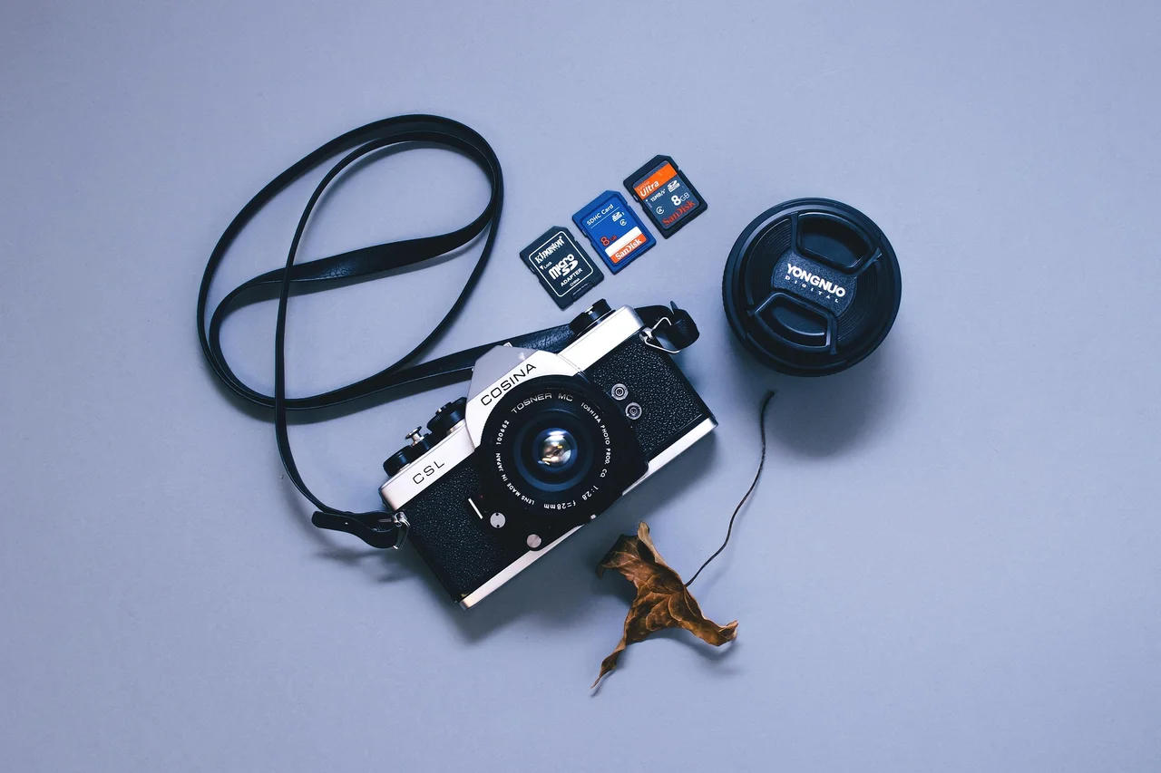 Camera memory cards beside a camera and lens